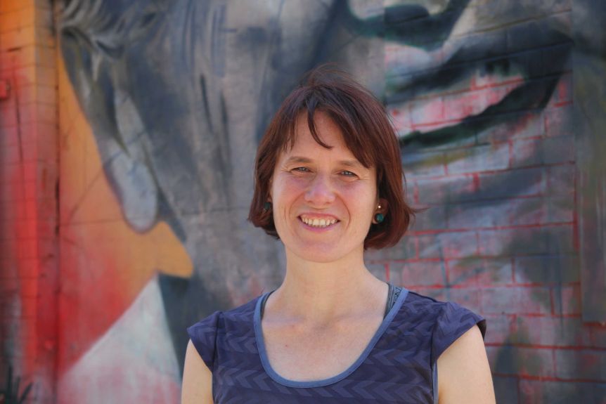 Lisa smiles into the camera, a mural behind her.