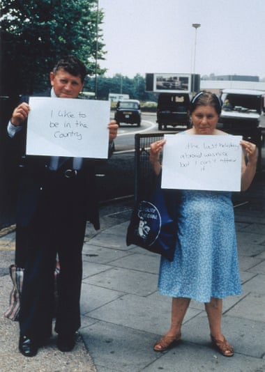 The couple holding up signs by the side of the motorway.