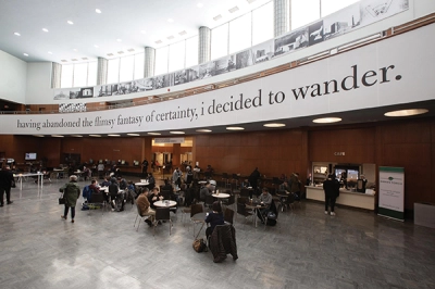 A large banner with a poetic quote hangs from the mezzanine in a library's lobby