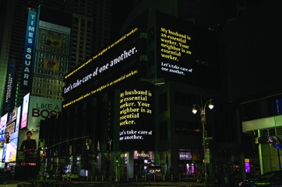 Electronic billboards in Times Square are lit up with white and yellow text at night