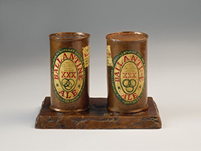 Two beer cans cast in bronze with the label designs painted over