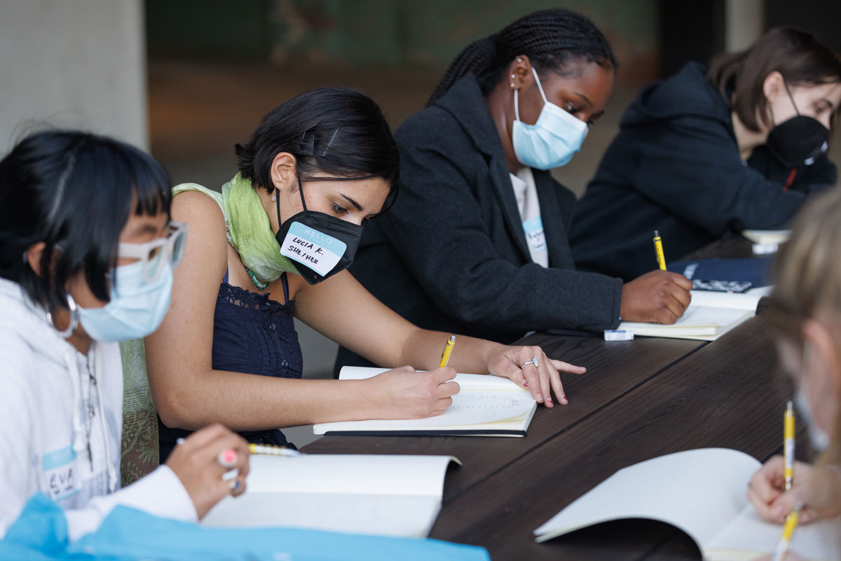 High school students wearing face masks write in notebooks.
