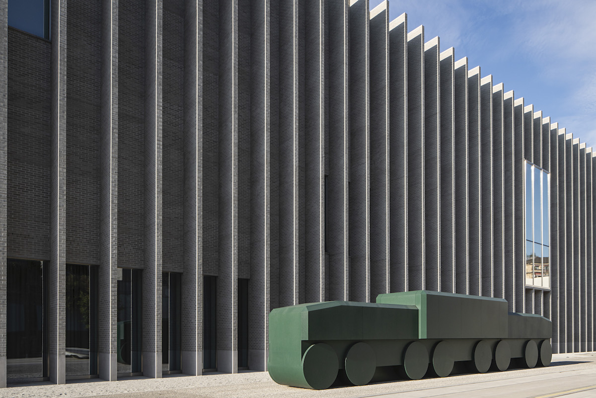 A building with a blocky sculpture resembling a train outside it.