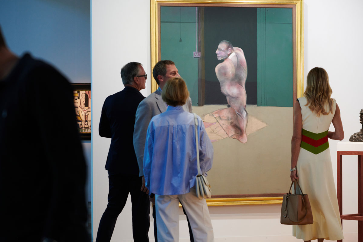 Several people stand in front of a large painting depicting a man whose body is contorted standing in front of a green door.