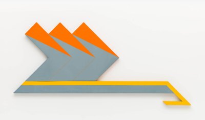 A shaped canvas consisting of three chevrons interlaid with each other, with their points facing right. They sit above a parallelogram that has a piece jutting out at the right. The painting is mostly a steely blue, but the chevrons have triangles of orange and the parallelogram has a top that leads into the jutting out part that is yellow.  