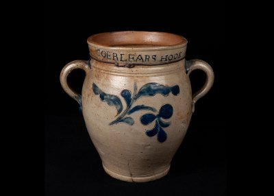 A ceramic jar with a blue floral detail on it. At its mouth reads Corlears Hook. 